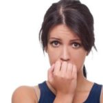 Woman with dark hair and fair skin covering her mouth, appearing anxious about air quality and coughing issues.