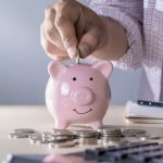 Piggy bank with a smiling face and coins on table, representing savings tips for home comfort and utility cost reduction.