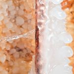 Ice forming around a copper pipe with water dripping, illustrating winter plumbing challenges and the risk of frozen pipes.