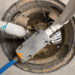 Backup sump pump system in a sump pit, featuring discharge pipes and water, illustrating flood prevention measures for basement protection.